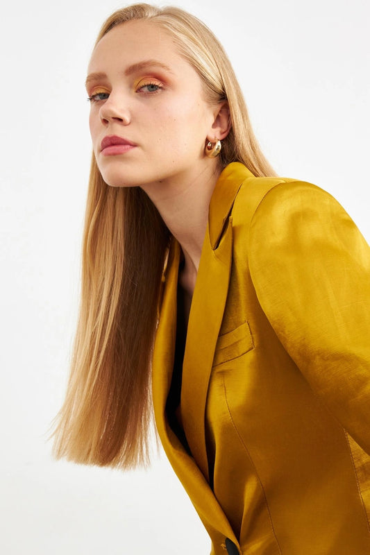 Model wearing a mustard colored silk suit, closeup